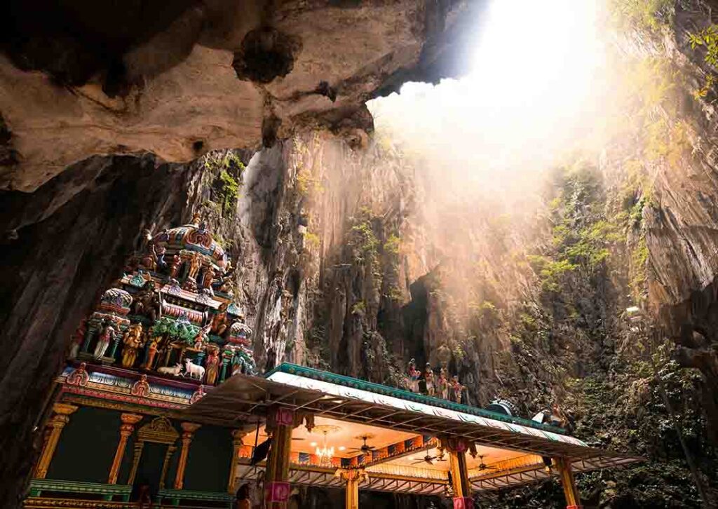 The towering limestone cliffs and the golden statue of Lord Murugan at Batu Caves, Malaysia